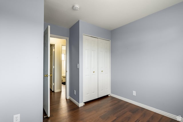 unfurnished bedroom with a closet, baseboards, and dark wood finished floors