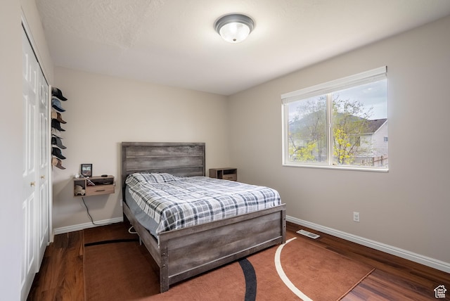 bedroom featuring wood finished floors, baseboards, a closet, and visible vents