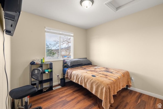 bedroom with visible vents, baseboards, attic access, and wood finished floors