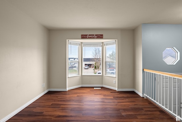 unfurnished room featuring dark wood-type flooring and baseboards