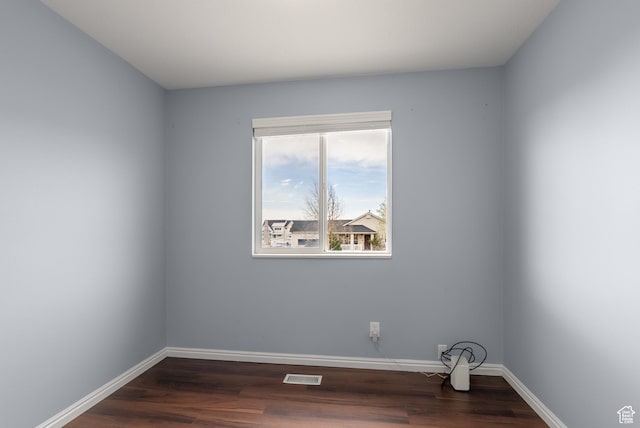 spare room with baseboards, dark wood finished floors, and visible vents
