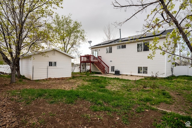 rear view of property featuring an outdoor structure, stairs, a patio area, solar panels, and a deck