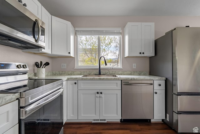 kitchen with a sink, white cabinets, dark wood-style floors, and stainless steel appliances