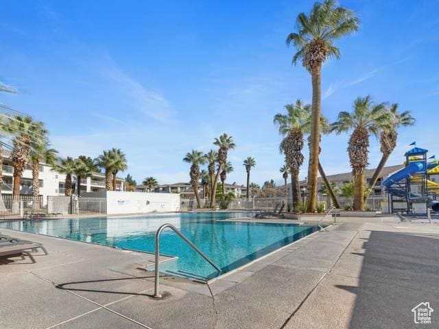 community pool with a patio area and fence
