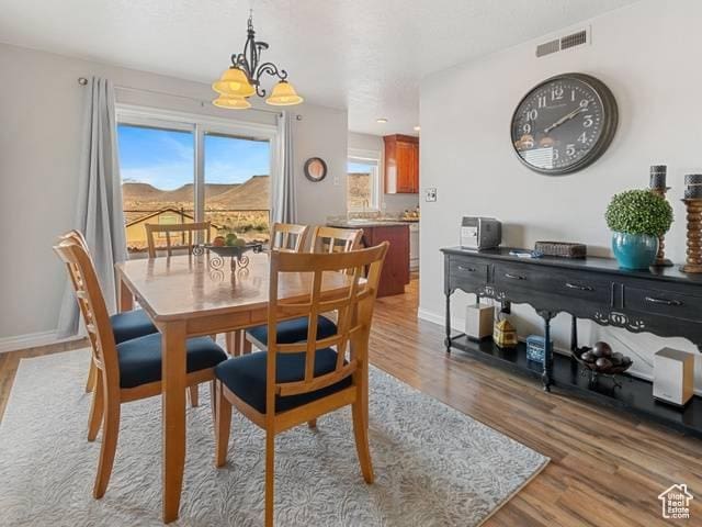 dining space featuring a notable chandelier, baseboards, a mountain view, light wood-style flooring, and visible vents