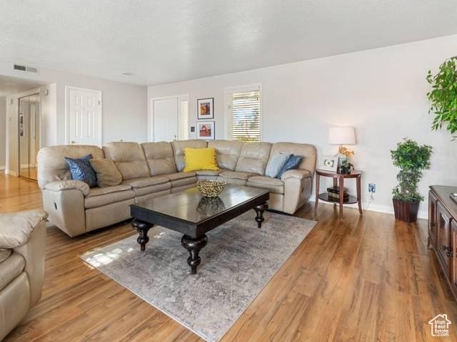 living area featuring visible vents, light wood-type flooring, and baseboards