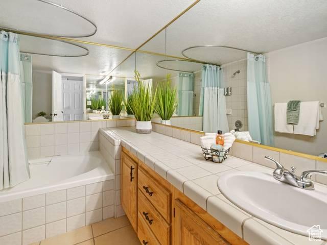 full bathroom featuring tile patterned flooring, curtained shower, vanity, and tiled bath