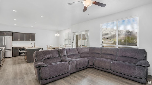 living room featuring light wood-style floors, ceiling fan with notable chandelier, and a healthy amount of sunlight