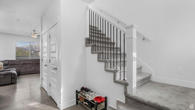stairway with wood finished floors, ceiling fan, and baseboards