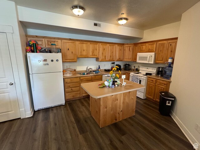 kitchen featuring a sink, dark wood-type flooring, white appliances, and visible vents