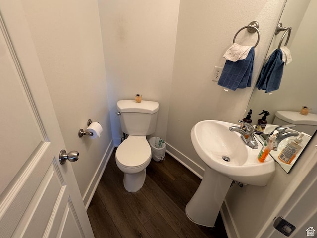half bathroom featuring toilet, baseboards, a sink, and wood finished floors