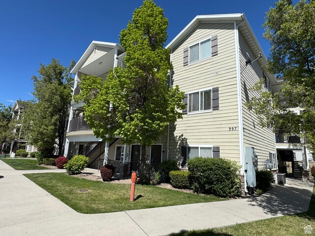 view of front of property featuring a balcony, stairs, and a front lawn