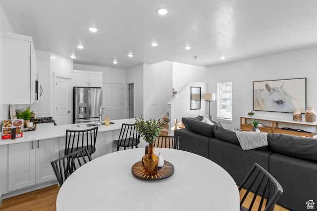 dining space featuring light wood-style flooring, stairway, and recessed lighting