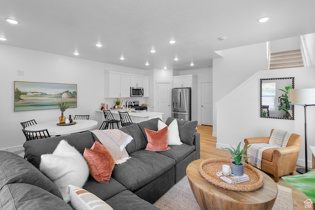 living room with recessed lighting, stairway, light wood-style flooring, and baseboards
