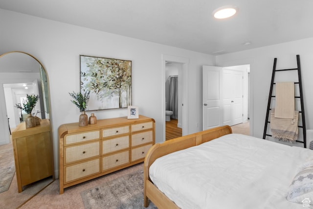 bedroom with light colored carpet and connected bathroom