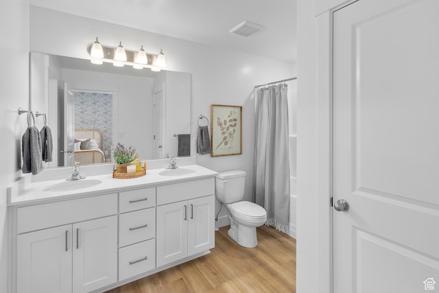 ensuite bathroom featuring a sink, visible vents, toilet, and double vanity