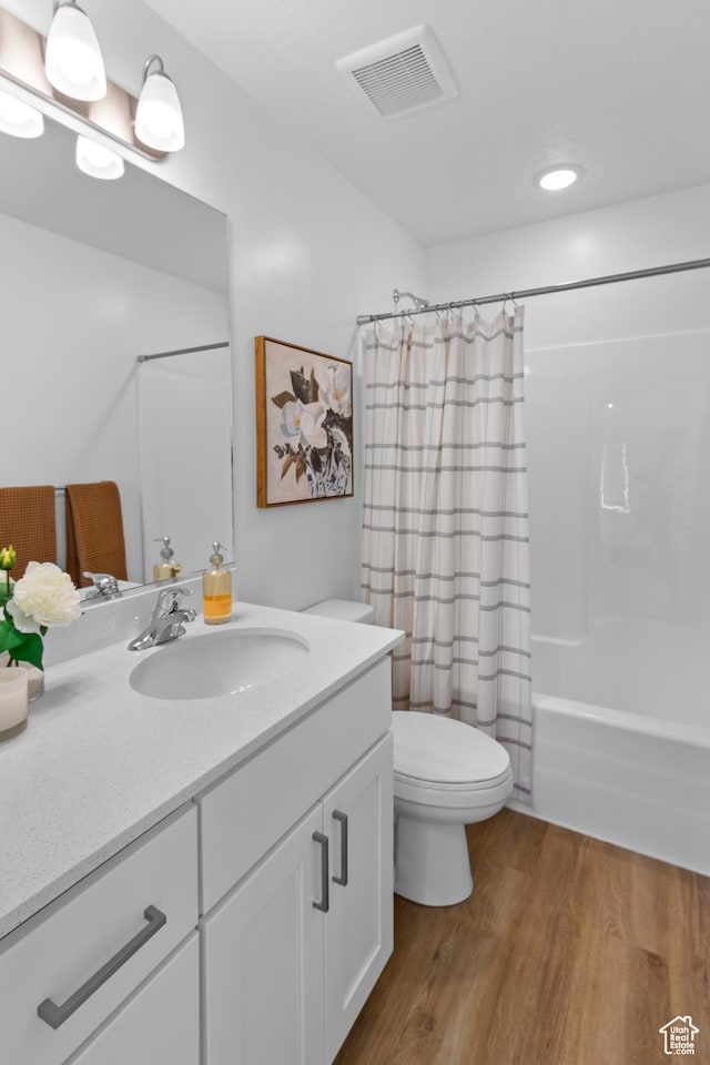 full bathroom with shower / tub combo, vanity, toilet, visible vents, and wood finished floors