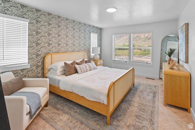 bedroom with visible vents, baseboards, light carpet, and wallpapered walls
