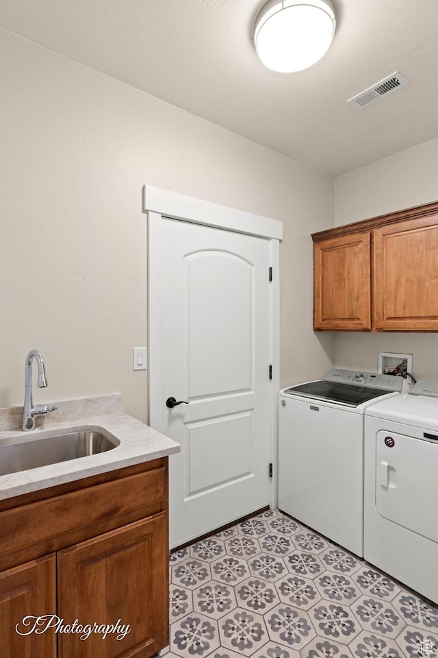washroom with separate washer and dryer, a sink, cabinet space, and visible vents