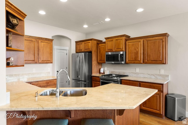 kitchen featuring a kitchen breakfast bar, a peninsula, open shelves, stainless steel appliances, and a sink