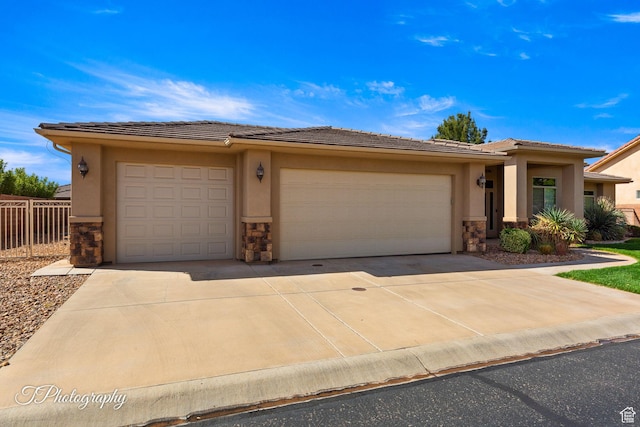 view of front facade with stucco siding, driveway, stone siding, an attached garage, and a tiled roof