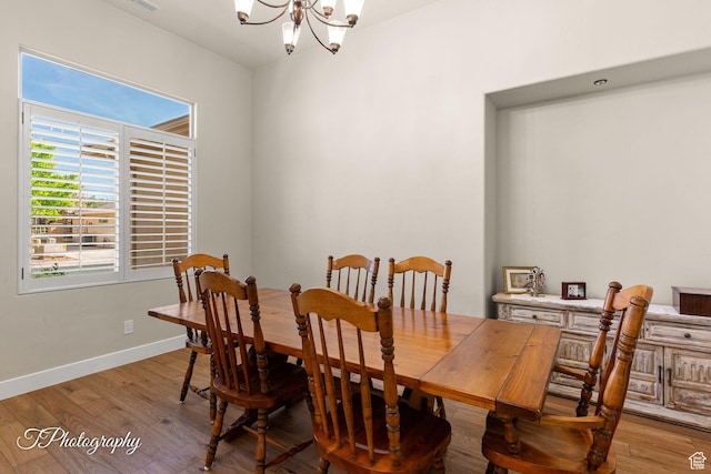 dining room with light wood finished floors, an inviting chandelier, baseboards, and visible vents