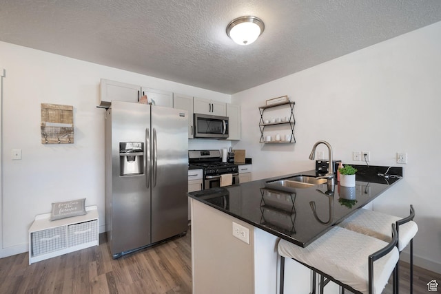 172 E Legacy Pkwy, Saratoga Springs, UT 84045 - kitchen with a peninsula, dark wood-style floors, a sink, appliances with stainless steel finishes, and a breakfast bar area