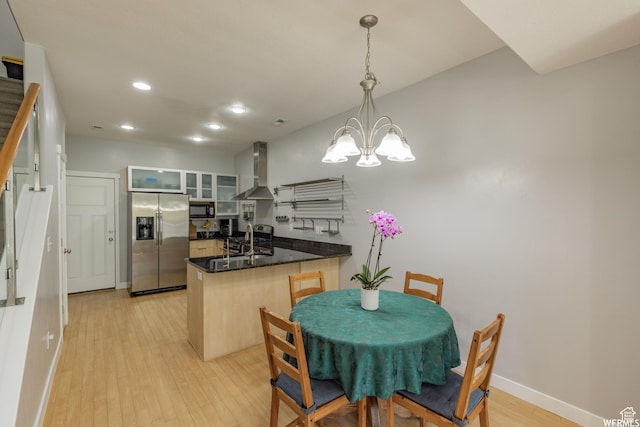 kitchen with a peninsula, stainless steel fridge with ice dispenser, wall chimney exhaust hood, and baseboards
