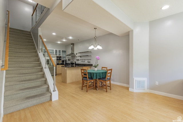 dining area featuring light wood-style floors, stairway, visible vents, and baseboards