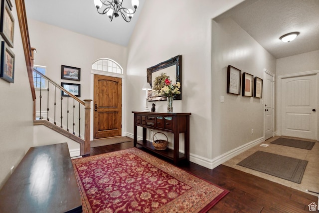 foyer entrance with baseboards, stairway, a chandelier, and hardwood / wood-style flooring