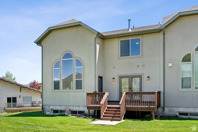back of property with roof with shingles, a yard, stucco siding, and a deck