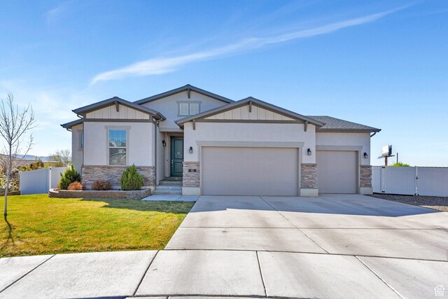view of front of property featuring stone siding, a garage, fence, a front lawn, and driveway