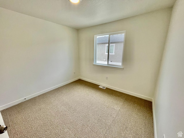 unfurnished room with dark colored carpet, visible vents, and baseboards