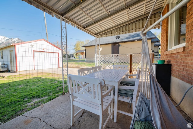 view of patio featuring an outbuilding, fence, and outdoor dining space