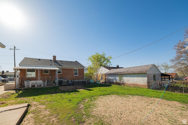 rear view of house featuring a yard, fence, a patio, and a chimney