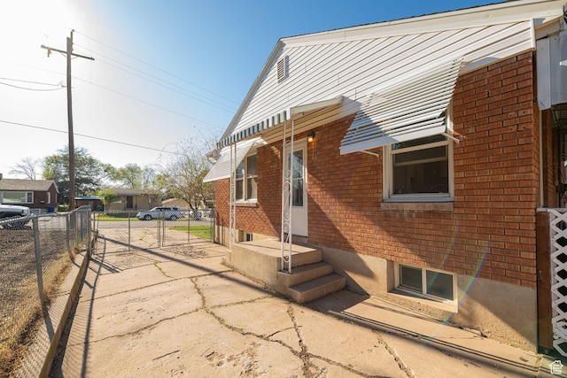 view of side of property with brick siding, fence, and a gate