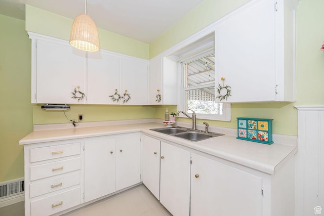 kitchen with visible vents, a sink, light countertops, white cabinetry, and pendant lighting