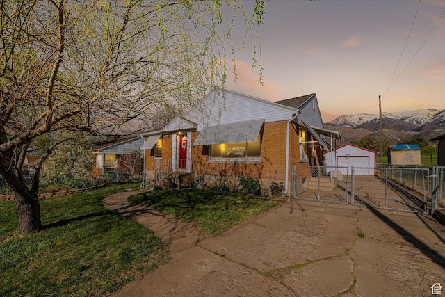 bungalow-style house with a garage, fence, an outdoor structure, brick siding, and a gate