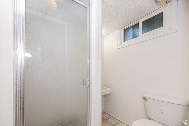 bathroom featuring toilet, a stall shower, a drop ceiling, and tile patterned floors