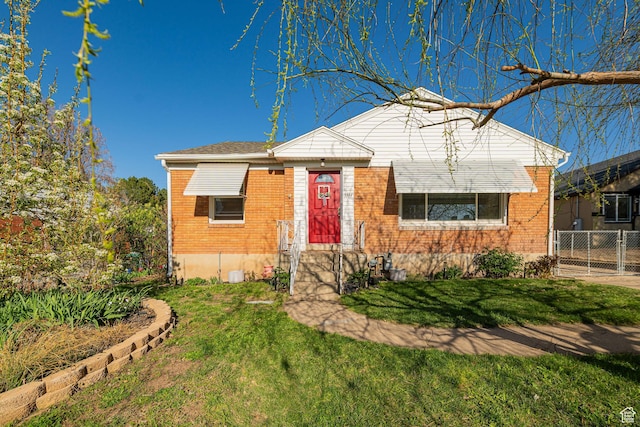 view of front of house featuring a front yard, fence, and brick siding
