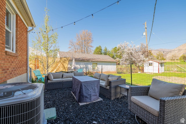 view of patio featuring an outdoor living space, central AC, fence, and an outbuilding