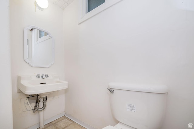 bathroom featuring a sink, baseboards, and toilet