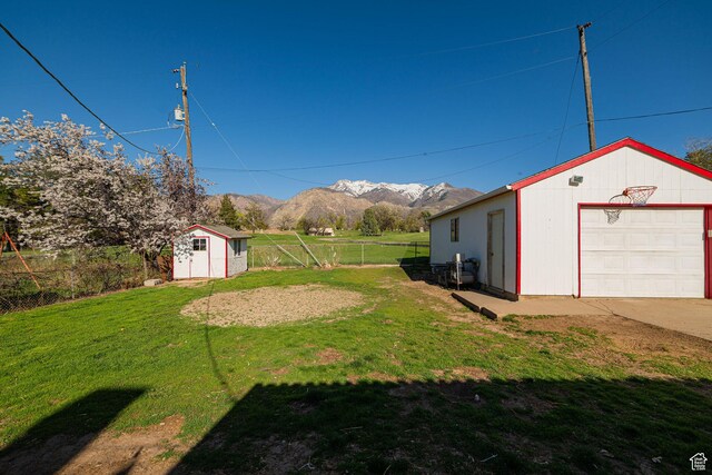 view of yard featuring fence, a mountain view, an outbuilding, and a garage