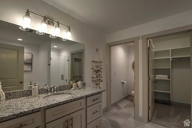 55 E Buttercup Ln Unit 42, Garden City, UT 84028 - bathroom featuring baseboards, toilet, a walk in closet, vanity, and a stall shower