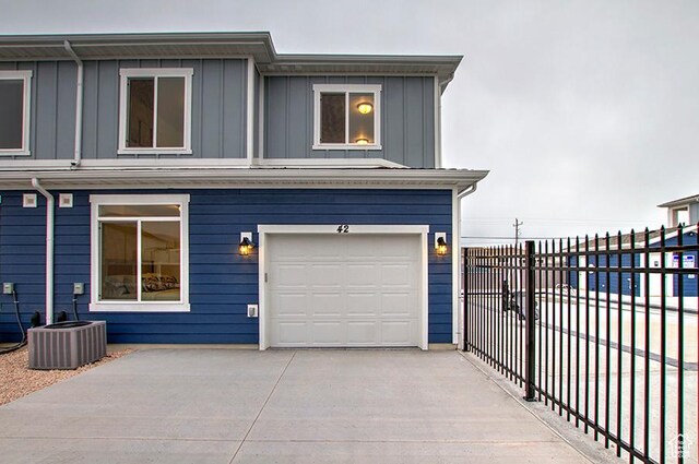 55 E Buttercup Ln Unit 42, Garden City, UT 84028 - view of front of home with concrete driveway, board and batten siding, an attached garage, central AC unit, and fence