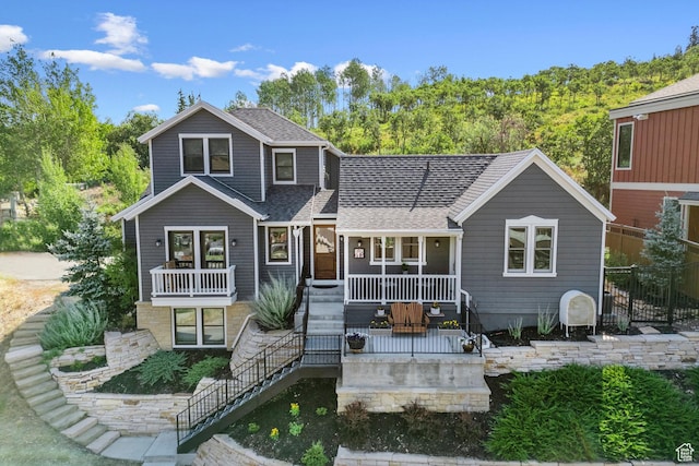 view of front of house featuring a porch, a shingled roof, and stairs