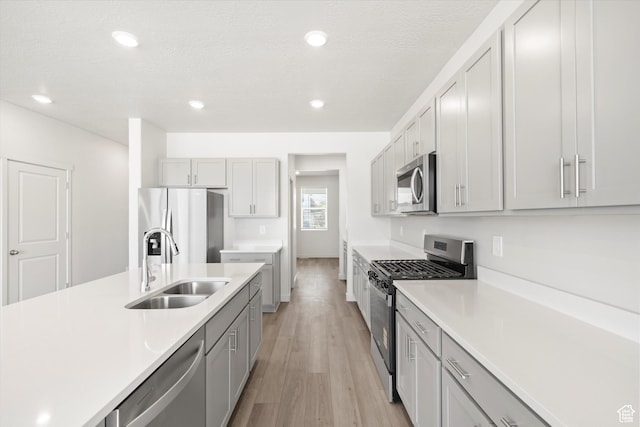 1345 N Harper Way Unit 0250, Tooele, UT 84074 - kitchen with stainless steel appliances, light countertops, light wood-type flooring, gray cabinets, and recessed lighting