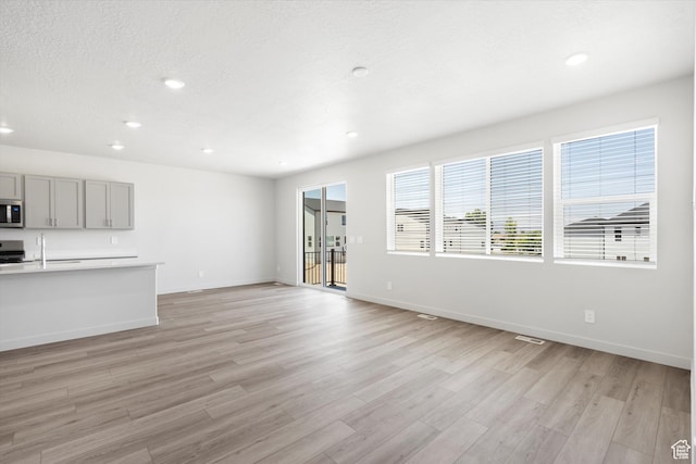 1345 N Harper Way Unit 0250, Tooele, UT 84074 - unfurnished living room with light wood-style floors, recessed lighting, and a textured ceiling