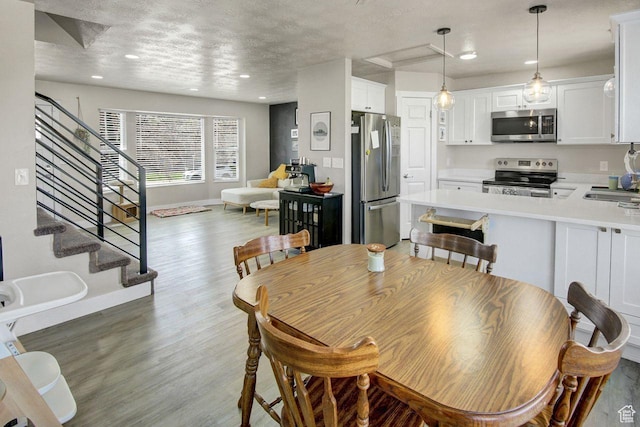 dining area with light wood-style floors, a textured ceiling, recessed lighting, stairs, and baseboards