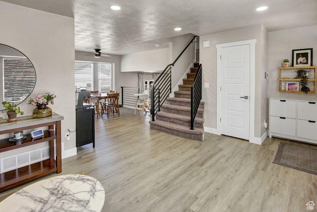 entryway with stairs, light wood-style flooring, baseboards, and a ceiling fan